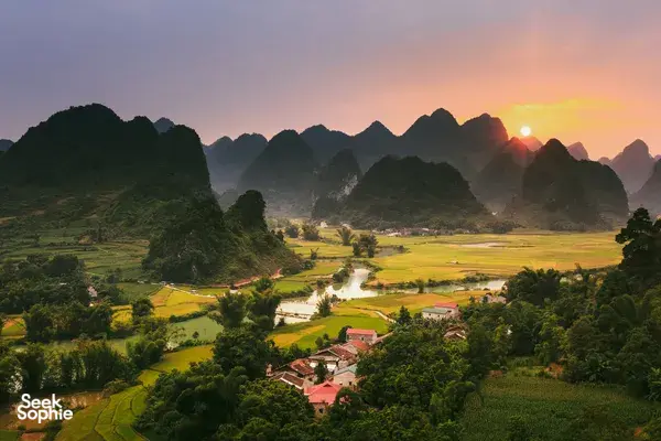 Cao Bang karst mountains at sunrise above terraced fields and a riverside village during the 3D3N motorbike loop