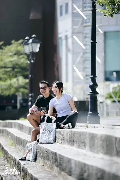 Players of a real-life Monopoly game taking a break by the Singapore River, smiling with game bags—Singapore hidden gems