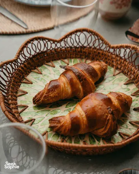 Croissant segar tersusun di dalam bakul anyaman di atas alas meja bercorak semasa bengkel French Cooking Lab di Singapura