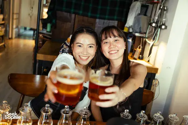 Two guests smiling and clinking amber whisky glasses at a small-batch whisky tasting in a hidden home bar in Singapore