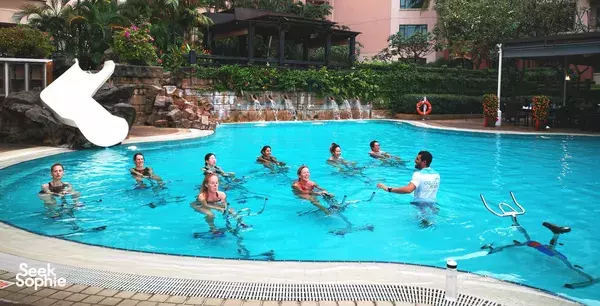 Group Aquaspin class in The Ripple Club pool, with aqua bikes and an instructor by the water at Paradox Singapore Merchant Court