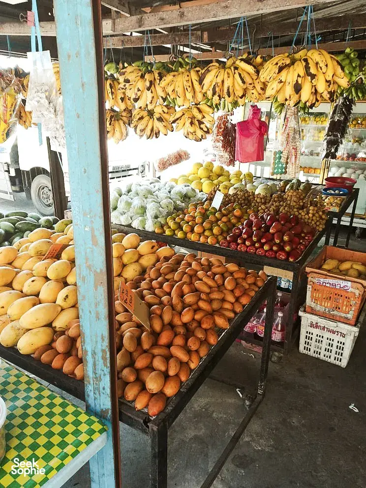 Colourful fruit market stall in Langkawi with hanging bananas and stacked produce, a stop on a cycling villages and markets tour