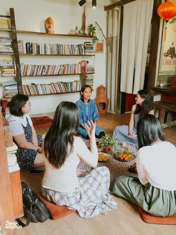 Sekelompok orang duduk melingkar mendengarkan tuan rumah berbagi budaya di Chan Dat Living Room, homestay nyaman di Hoi An