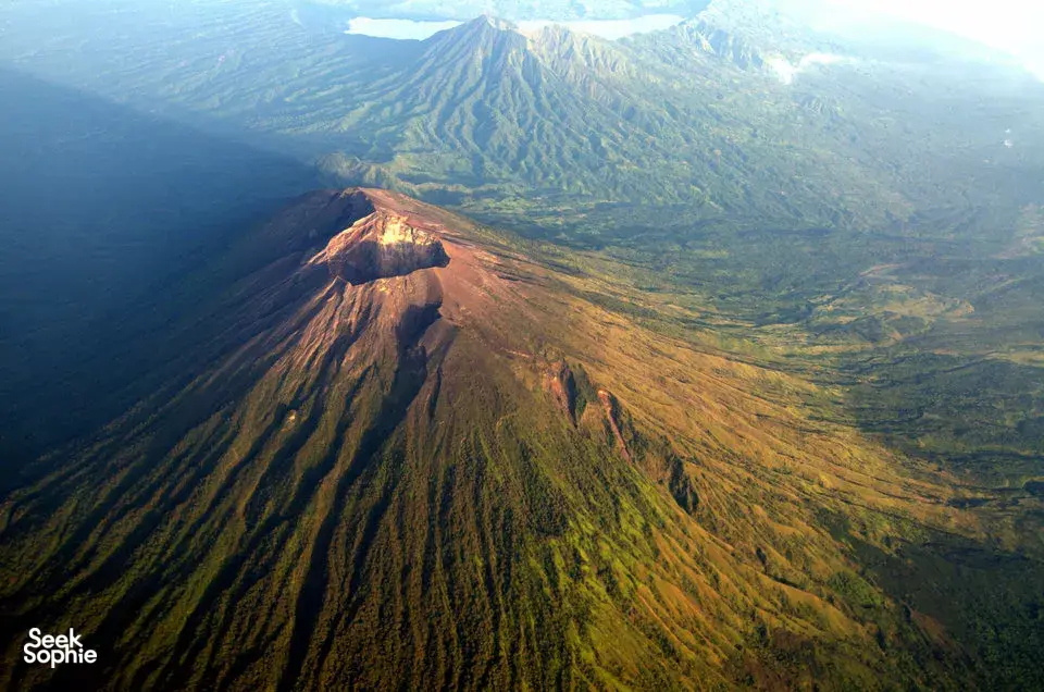 Aerial view of Mount Agung’s rugged ridge and crater at Bali sunrise, with valleys stretching into the distance