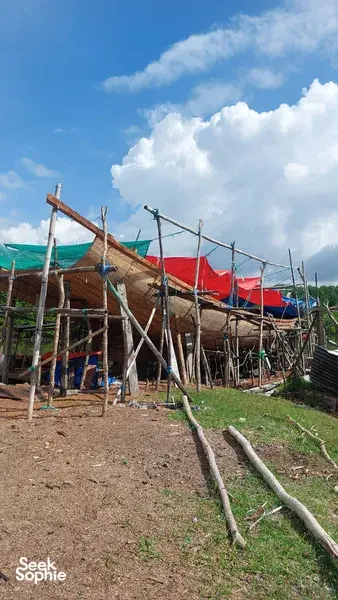 Bot kayu yang dimamah cuaca dan jala yang dijemur di sepanjang pesisir tanah, di bawah langit cerah di pinggir Labuan Bajo