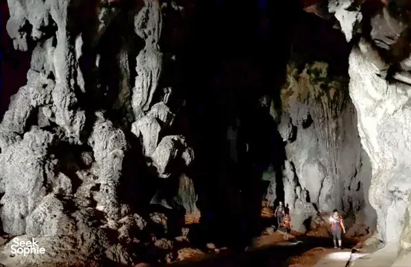 Rocky cave entrance with travellers walking along a dim chamber near Kuching on a gold-mine and jungle adventure