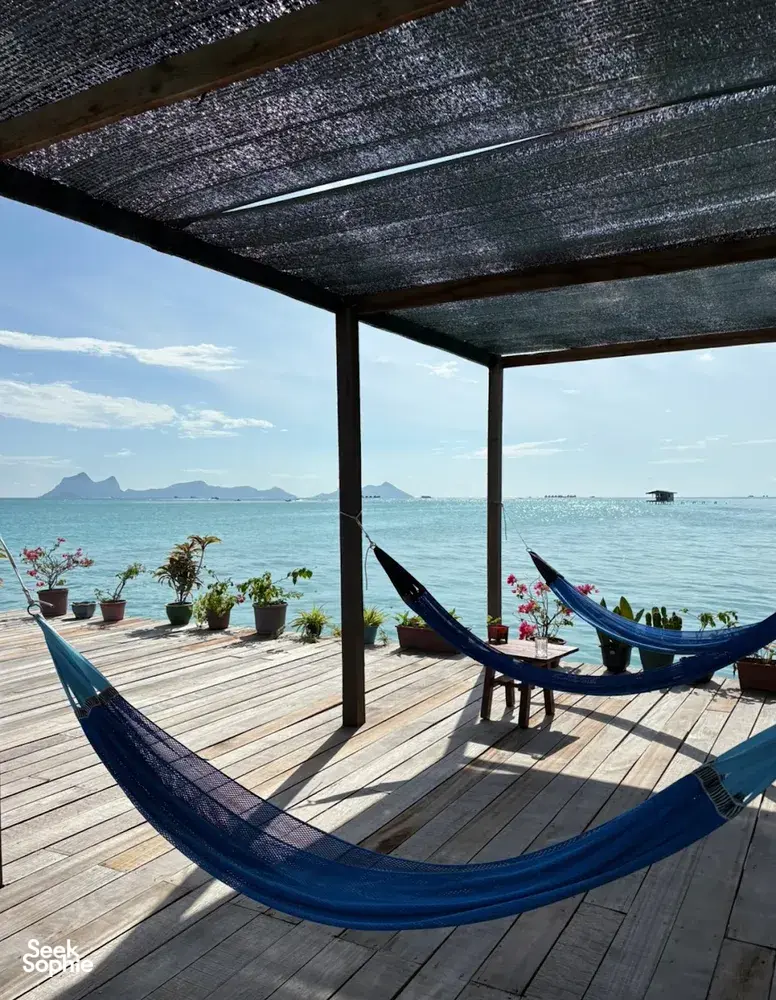 Buaian hammock di dek terbuka banglo air di Semporna, menghadap laut dan bukit di kejauhan semasa menginap di Bigfin Divers