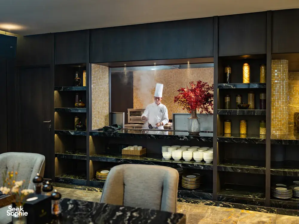 Chef in a luxury restaurant of Doris Cruise presenting breakfast at an open buffet with warm lighting in Halong Bay