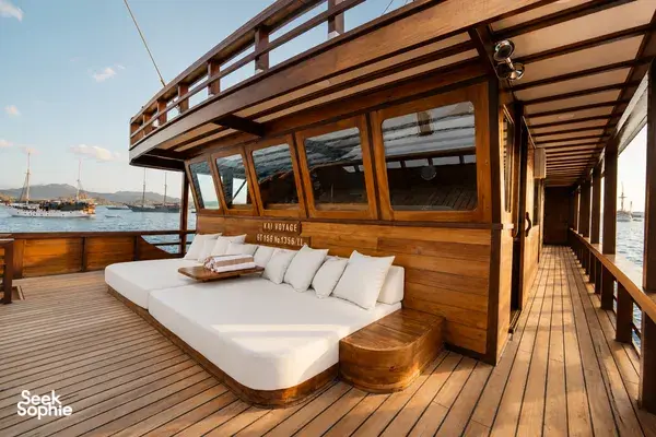 Forward deck sunbed of a Travass Life phinisi with built-in cushions and wooden railings, departing at sunrise in Labuan Bajo