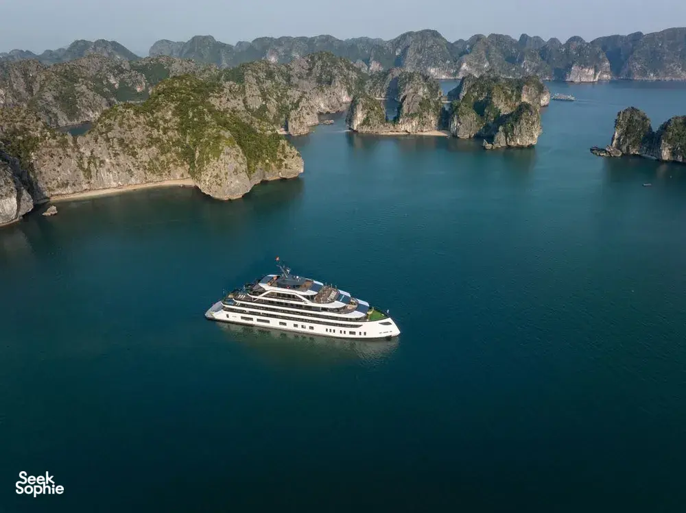 Aerial view of the Doris Cruise ship floating in Halong Bay’s calm waters beside towering limestone karsts on a 2D1N cruise
