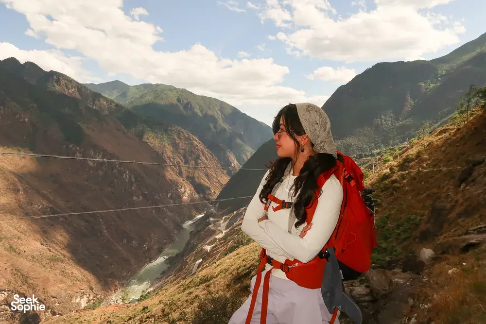 Backpacked hiker gazing over a mountain valley on the high trail of Tiger Leaping Gorge, Lijiang, hosted by The Bivou Lijiang