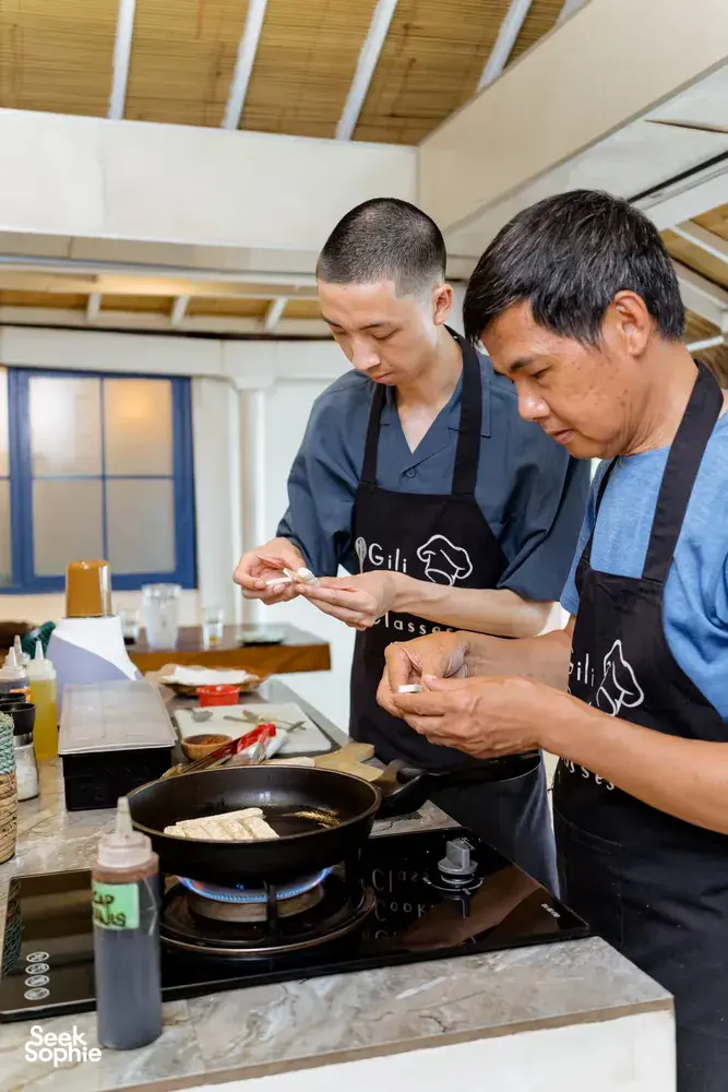 Host-led cooking class on Gili T, Lombok: participants pan-fry ingredients while learning to make peanut sauce