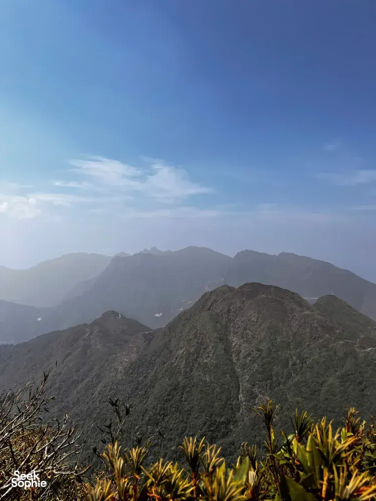 Mountain ridges under a clear blue sky with misty layers beyond, captured during a 1-day eco trek at Mt Fansipan