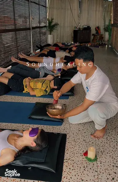 Quiet sound-healing session in a studio in Canggu, with participants lying on mats as a host plays a singing bowl