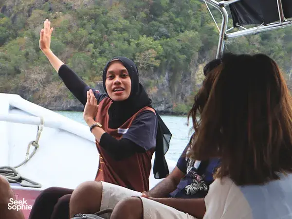 JungleWalla Langkawi naturalist gesturing on a Langkawi cruise boat, explaining the UNESCO Geopark scenery to passengers