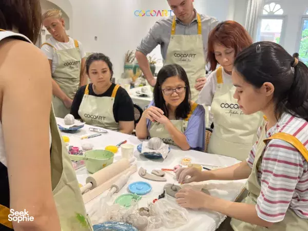 Group pottery class at a bright art studio in Singapore, students moulding clay at worktables during a 2-in-1 session workshops in Singapore
