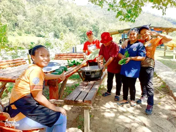 Team preparing riverside lunch at a rustic cooking station, with Outreach Borneo, during a jungle adventure near Kota Kinabalu
