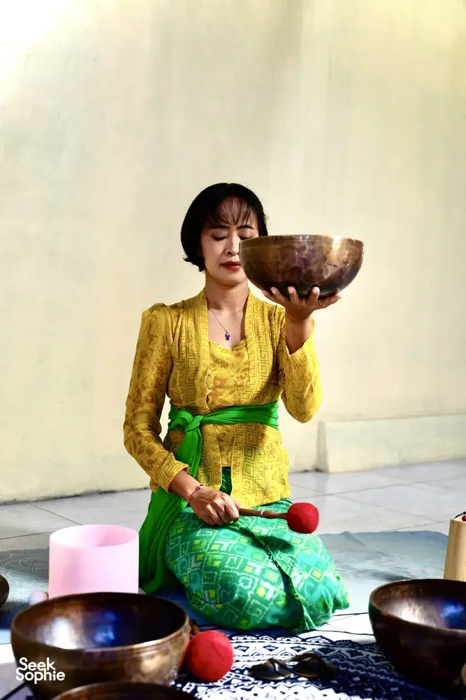 ADDA Yoga sound healing in Canggu: a practitioner holds a singing bowl while seated on a floor mat during a mindfulness session