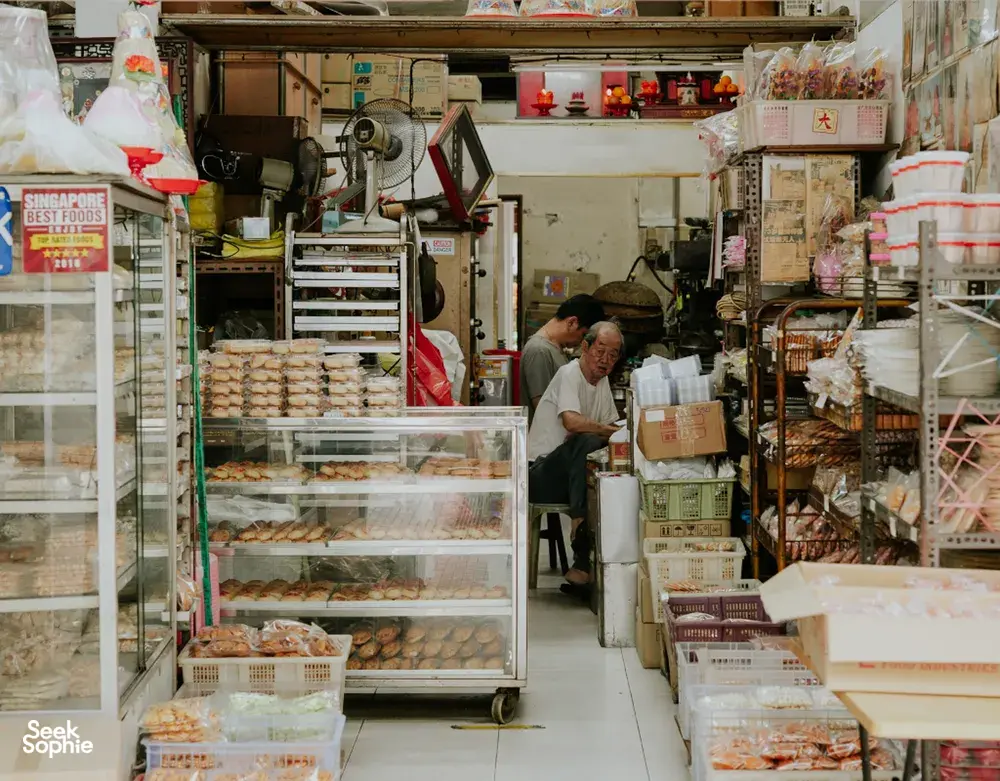 Pemandangan lorong sempit di dalam kedai dengan snek berkotak dan barangan dapur, untuk kisah Hidden Heritage di flat sewa serta tempat tersembunyi di Singapura