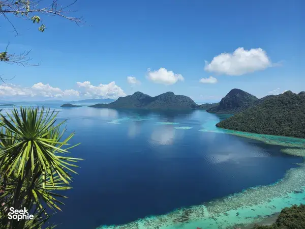 Blue bay with turquoise shallows and forested mountains near Semporna, Sabah, viewed from the Bohey Dulang hike