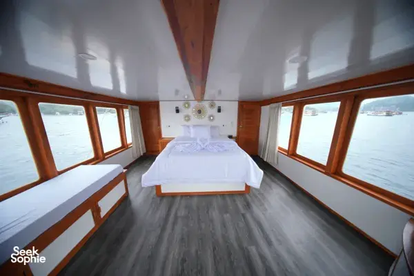 Spacious onboard cabin with a neatly made double bed and decorative wall lights on a join-in 3D2N Komodo trip, near Komodo Island