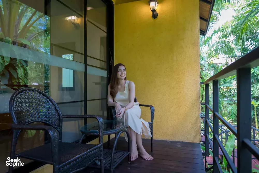 Anurak Lodge verandah with a guest relaxing in wicker chairs, surrounded by lush rainforest greenery near Khao Sok National Park