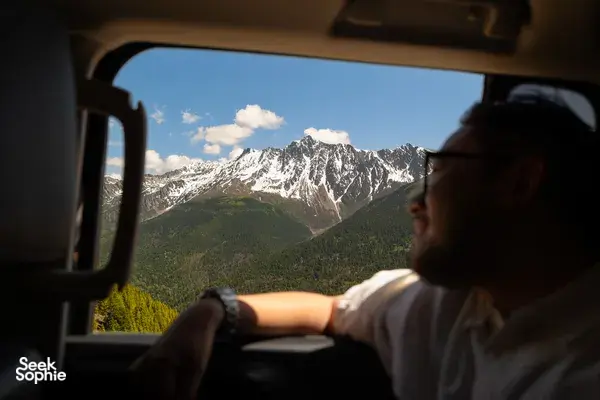Traveller gazing from a vehicle window at snow-capped peaks near Shangri-La during a 6-day Loop with a Tibetan guide