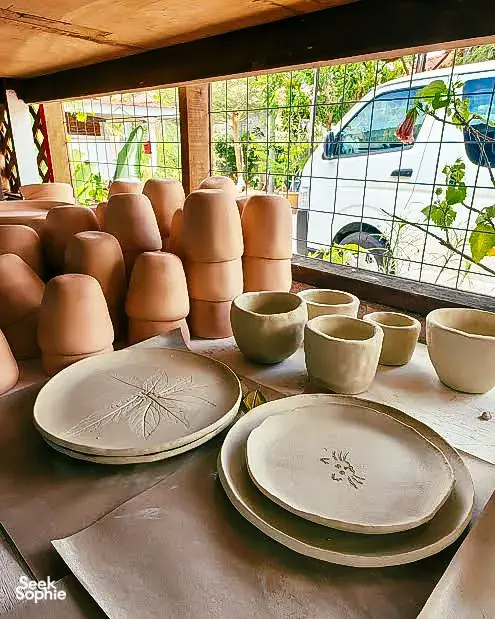 Inside Ilham Ceramic Studio in Langkawi, rows of unglazed cups and plates sit on shelves by large windows