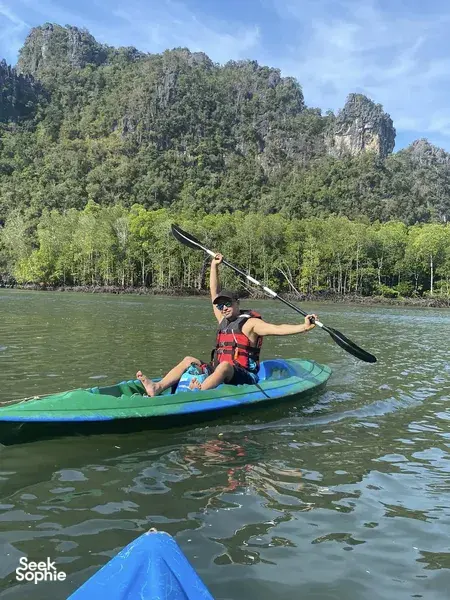 Kayakers paddling through Kilim Geoforest river with a naturalist guide on Langkawi, passing green jungle hills