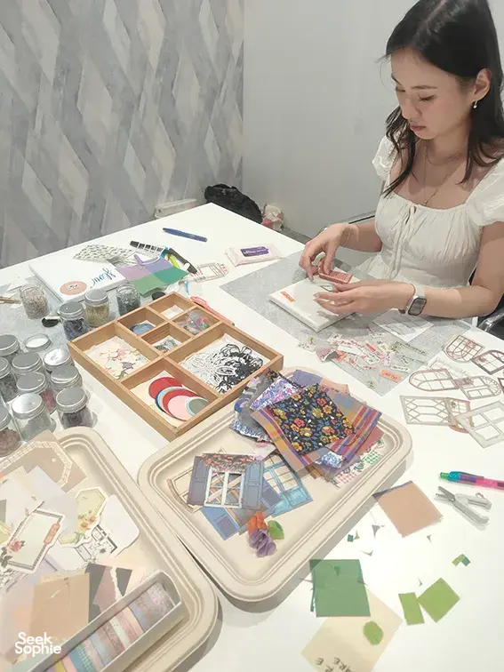 Vision-board crafting at a Gemstory workshop table as a participant assembles collage pieces for workshops in Singapore