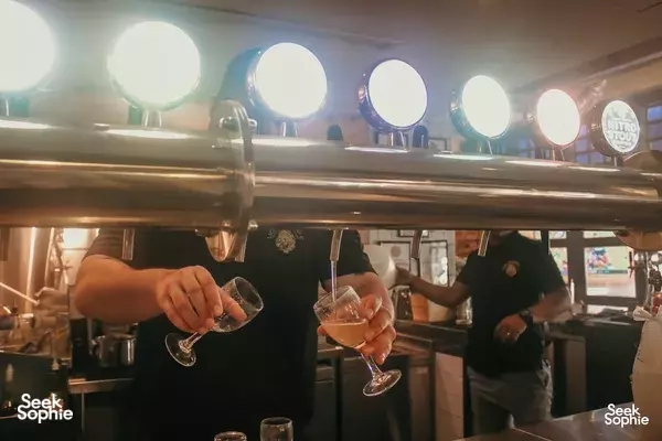 Bartenders pouring beers at Lion Brewery Co brewpub in Singapore, with glowing circular lights above the bar
