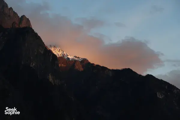 Twilight mountain ridges over Tiger Leaping Gorge near Lijiang, with clouded sky glowing beyond the trail during the 2D1N high hike