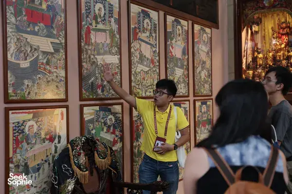 Hey Lad Tour guide pointing to colourful temple murals for guests during Hidden Chinese Rituals at night in Singapore, Singapore hidden gems