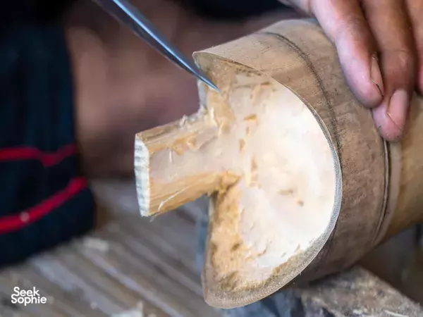 Bamboo Creative Bali in Bali: close-up of a knife carving a notch into a bamboo section on a woven surface.