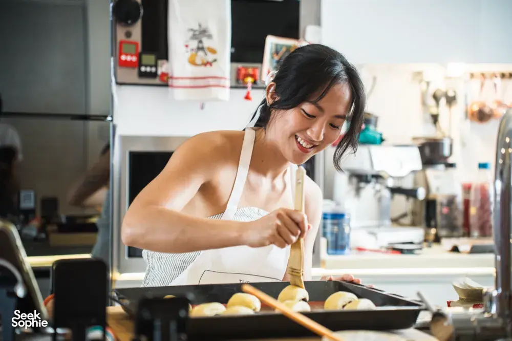 Baker shaping croissants at a kitchen counter in Singapore with a French Cooking Lab guide, workshops in Singapore