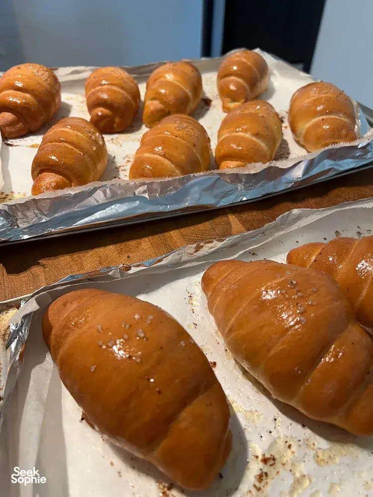 Glossy baked shio pan rolls cooling on a parchment tray during an intimate hands-on class for workshops in Singapore