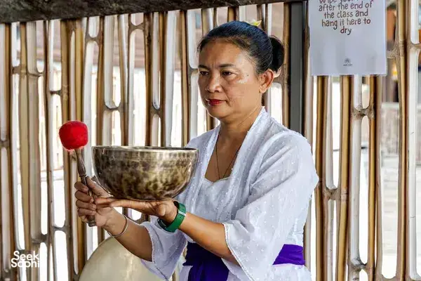ADDA Yoga practitioner holding a singing bowl with a wooden mallet in Canggu, Bali during rooftop sound healing