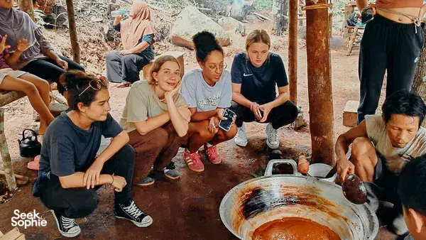 People gather around a large cooking pot outdoors in Lombok during the Lombok Forest Tour’s included cooking experience
