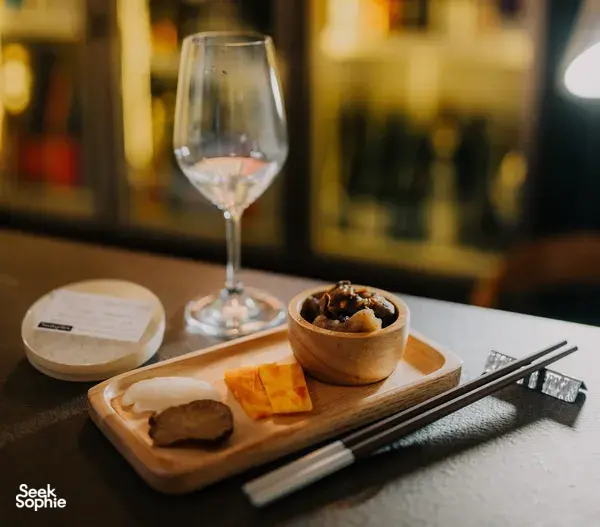 Sake tasting set-up in a tucked-away Singapore shop: crystal glasses, chopsticks and small dishes on a wooden board