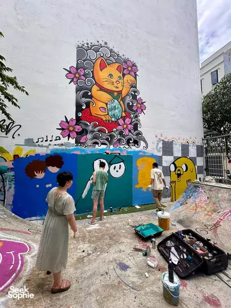 Artists preparing a mural on a Da Nang workshop wall, with paint supplies and tools on the courtyard floor