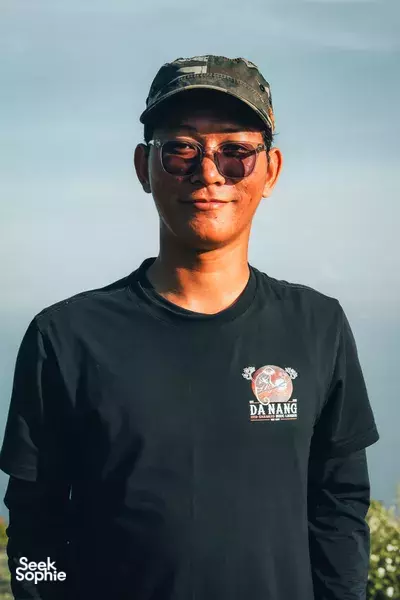 Tam Do of Da Nang Adventures poses outdoors in Da Nang, wearing a cap and sunglasses against an open blue sky