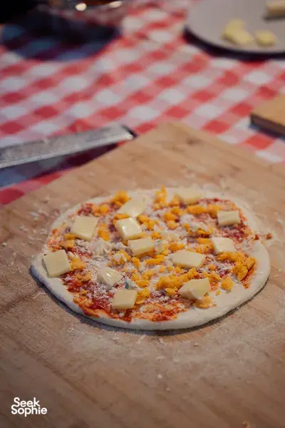 Topped pizza on a wooden board ready for the oven at Secret Pizza Club, for private dining Singapore