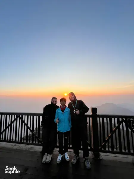 Travellers posing on a balcony at sunset above Sapa after a guide-led 1-day eco trek viewpoint, Mt Fansipan