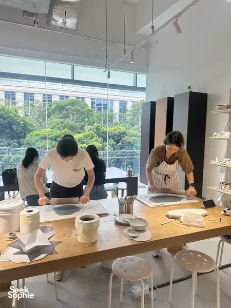Ceramics workshop scene with a small group shaping and painting ceramic plates at worktables during workshops in Singapore