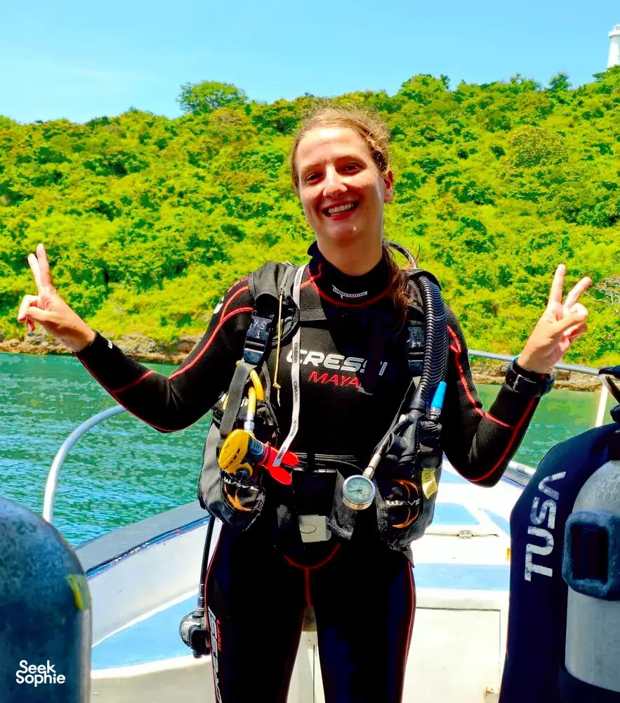Scuba Froggy diver smiling with peace signs in scuba gear on a boat in Lombok, ready for macro dives at Pink Beach