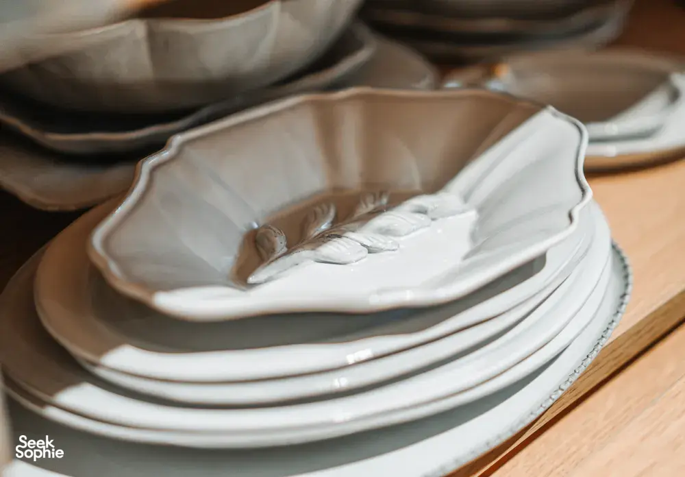 Stack of white embossed ceramic plates on a wooden table, created with antique-style detailing for everyday dining in Singapore