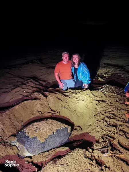 Travellers posing on steep rocky ground under bright lights at night on a guided Bromo–Ijen itinerary, Mt Ijen