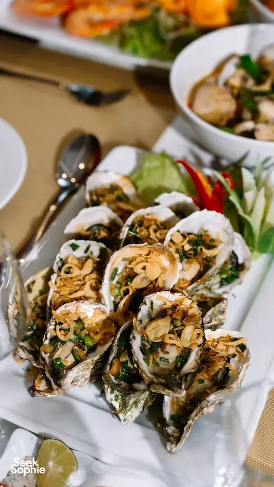 Seafood appetisers on white plates at a private dining table inside a Cat Ba luxury cruise cabin by Sunshine Golden Cruises