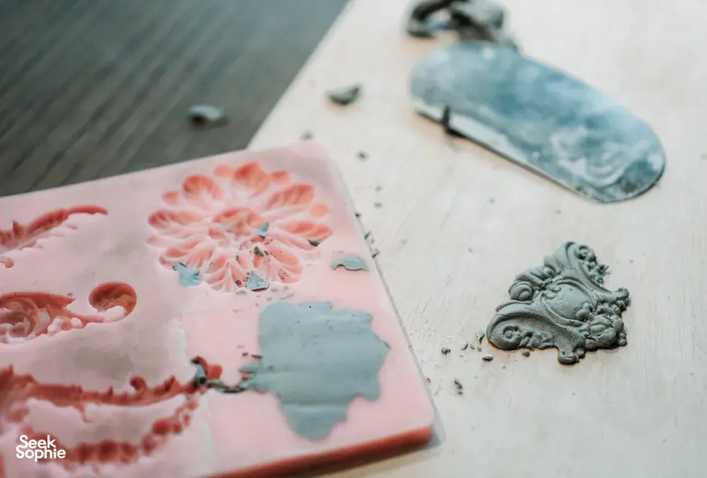 Glazed ceramic plate pieces with floral and decorative moulded details on a studio table during Ina Atelier workshops in Singapore