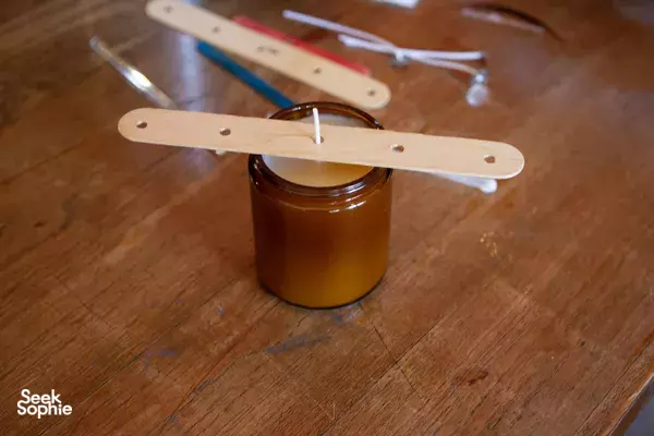 A candle jar with a wooden wick-holder tool on the tabletop for a Singapore candle workshop by Vcube Scenting
